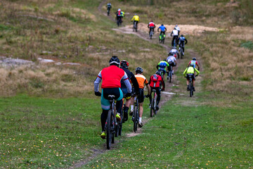 Group cyclists riding uphill behind each other at mountain bike competition