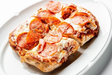 Rectangular pepperoni pizza with golden crust, melted cheese, and tomato sauce, served on a white plate, cut into square slices. Classic comfort food, top view