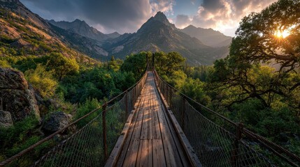 Obraz premium Wooden suspension bridge in mountain valley sunset