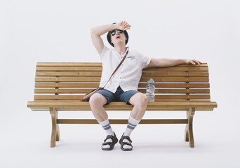 Middle-aged male tourist sitting on a bench, suffering from the heat. Concept of climate change.