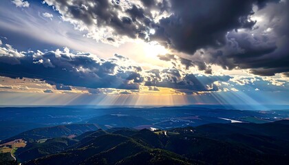 Dramatic sky view over a mountainous landscape. Sunbeams piercing through dark clouds