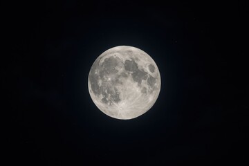 Fototapeta premium Celestial Sphere: Capturing the ethereal beauty of a full moon, a celestial marvel in the vast expanse of the inky blackness. This high-definition photograph embodies the night's serene stillness.