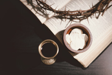 Communion bread and wine with the Holy Bible and crown of thorns, symbolizing the sacrifice of...