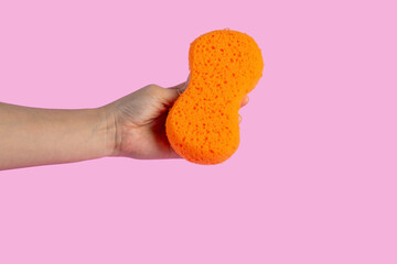 Sponge for cleaning in hand isolated on pink background.