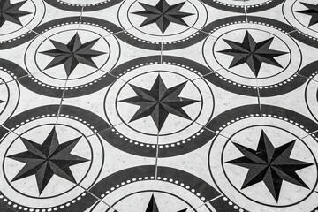 Intricate black and white geometric tile pattern with repeating starburst motifs and wavy lines