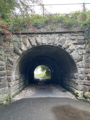 A weathered stone tunnel with a walkway leading towards the light.
