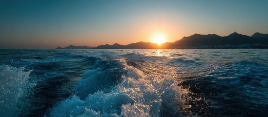 Sunset over the sea with foamy wake
