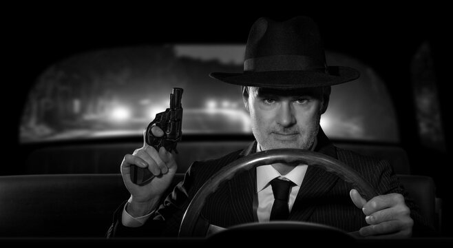 Detective with a gun in hand chasing criminals in his car, scene in 1950s American film noir style.
