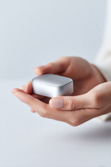 Womans hands gently hold a sleek, modern silver device. A concept for innovation, care, technology, and precious gifts. Perfect for product showcases, minimalism.