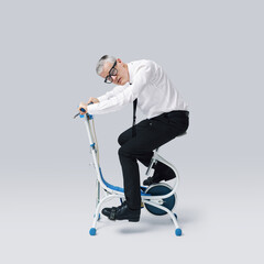 Exhausted weak businessman riding a stationary bike