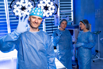 Surgeons celebrating success. A cheerful surgeon gives an okay sign as colleagues celebrate their...