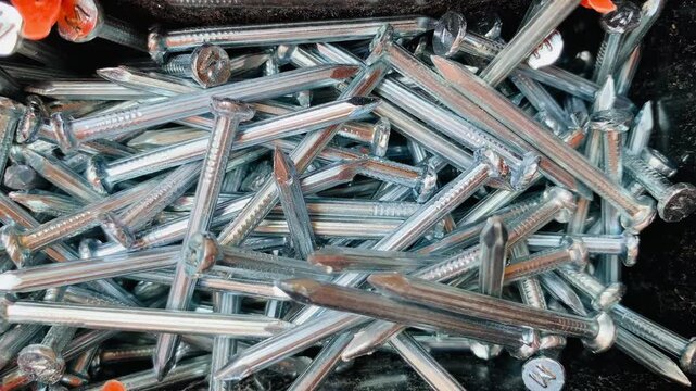 4K close-up of silver steel nails stacked in black box, sharp metallic detail and texture. Perfect for construction, carpentry, repair, DIY, hardware, and industrial themes.