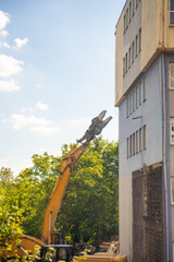 Demolition excavator using hydraulic jaws to dismantle a concrete building at a construction site....
