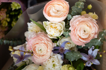 Bouquet of pink ranunculus and white roses with purple clematis and greenery