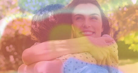 Hugging couple smiling in sunlit garden, featuring pastel polka-dot blouse and light blue shirt