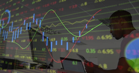 African American man reviewing market data at office desk, with tablet laptop overlay, copy space