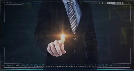 Fototapeta premium Pointing executive wearing dark suit, tie touching glowing amber dot on interface wall in studio