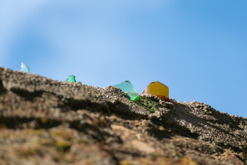 Broken glass shards protecting wall top under blue sky