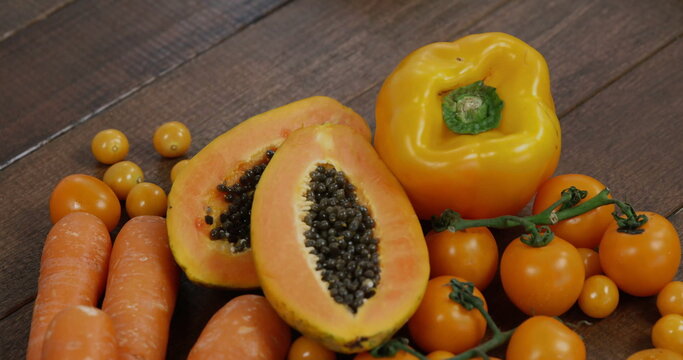 Showing halved papaya resting on wooden table, with carrots, yellow bell pepper and cherry tomatoes - Powered by Adobe