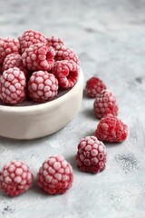 Frozen Raspberries in Bowl on Gray Textured Background for Healthy Treats and Culinary Arts.