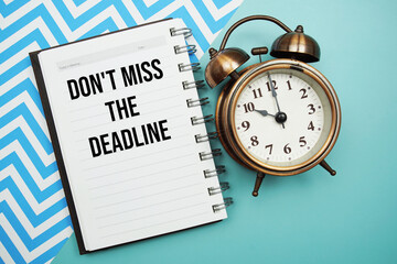 Don't Miss The Deadline text written on notepad with alarm clock