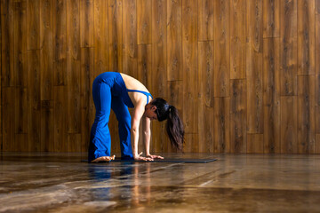 Young woman practicing yoga forward bend pose in studio