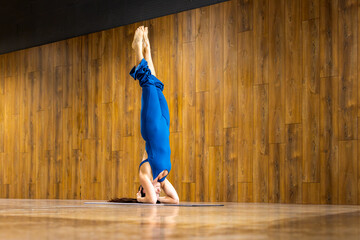 Yoga instructor performing supported headstand in studio