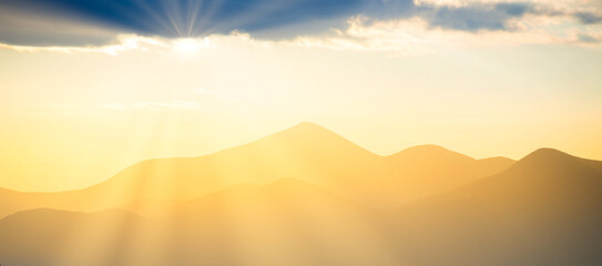 Sunset panorama in mountains. Landscape dramatic  sunset with mountains and sun shining through clouds