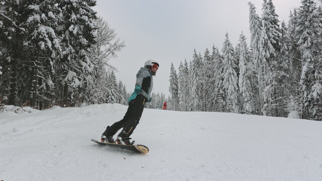Woman snowboarding on ski slopes in foggy forest. Travel, tourism, holiday, sports, active lifestyle. Bukovel ski resort, Carpathians, Ukraine. Slow motion