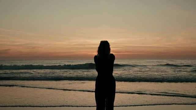 A peaceful silhouette of a person contemplating by the ocean, evoking feelings of serenity and reflection during a stunning sunset view.