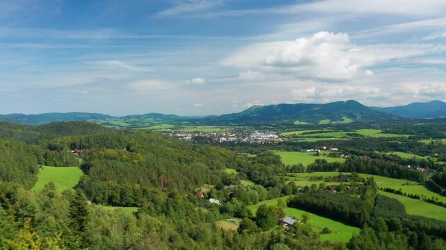 Reveal drone shot over trees of czech small city with beskydy mountains