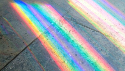 Diagonal bands of refracted light paint a rough, tiled surface with vibrant rainbows of color. The light creates a luminous, ethereal effect