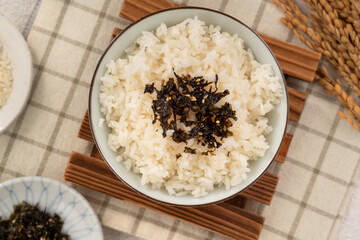 A bowl of white rice topped with seasoned seaweed and white sesame.