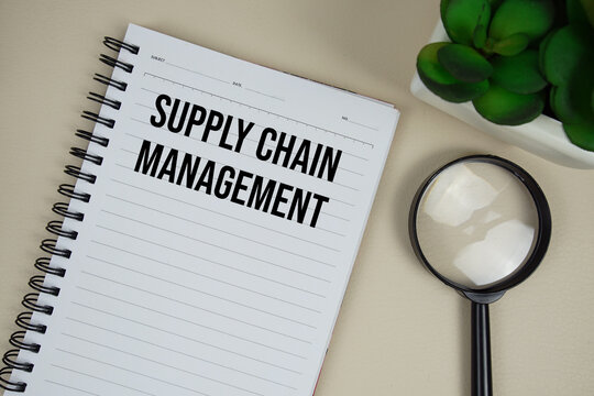 Supply Chain Management (SCM) text on paper notebook with magnifying glass on beige leather background - Powered by Adobe