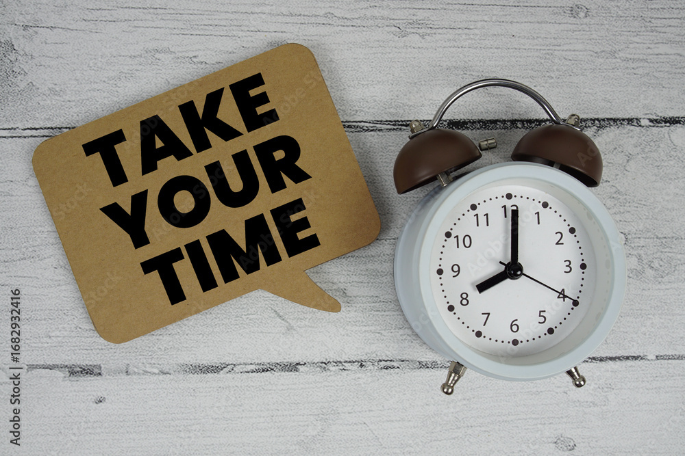 Poster take your time text with alarm clock on wooden background