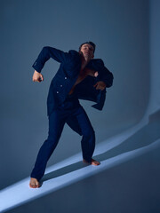 Male dancer moving forward in suit with clenched arms and emotional inner conflict. Concept of...