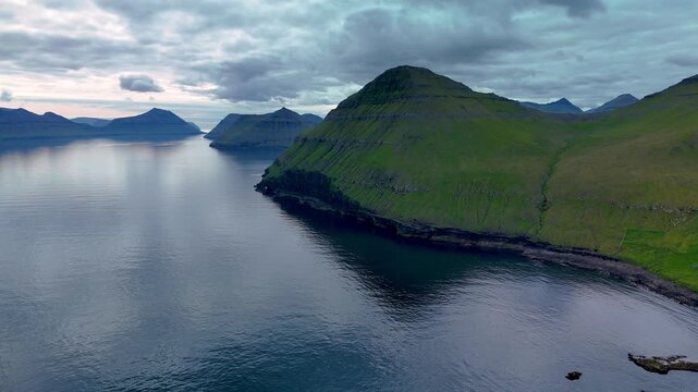 Explore the breathtaking beauty of Tjornuvik, featuring dramatic cliffs and calm waters under a moody sky. A perfect location to capture the tranquility of nature at twilight.