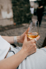 Woman sitting outdoors in casual attire, savoring glass of chilled white wine while enjoying peaceful moment of relaxation amidst vibrant urban backdrop. Woman relaxing outdoors, holding white wine