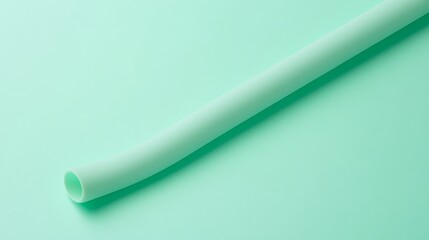 A close-up of a silicone straw with a smooth matte finish curved form laying on a solid mint green background kid-friendly