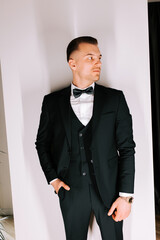 Sophisticated man in a formal suit posing elegantly against a wall