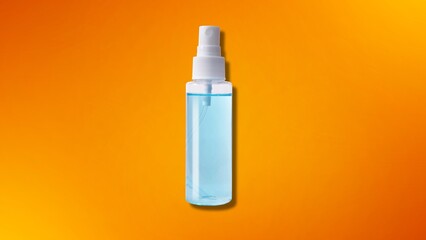 A clear plastic travel-size spray bottle with a white nozzle, filled with a light blue liquid for beauty or sanitizing purposes, on an orange background