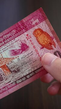 Vertical macro shot of man's hands and Sri Lanka rupee (LKR) banknotes. Concept of saving money for retirement, cash settlement, financial success, literacy and income planning in Sri Lanka.