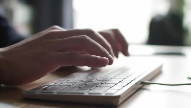 Typing on Keyboard: A close-up captures a person's hands deftly maneuvering across a minimalist keyboard, illuminated by the soft glow of natural light, focused work and technology
