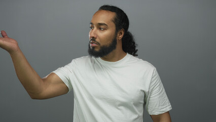 Bearded man shrugging with raised palms and closed eyes in a gray studio, neutral expression and...