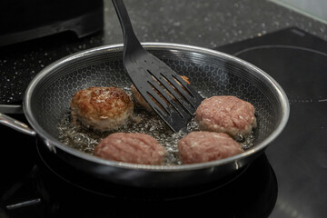Freshly prepared cutlets expertly brown and sizzle in a textured non-stick frying pan on a modern...
