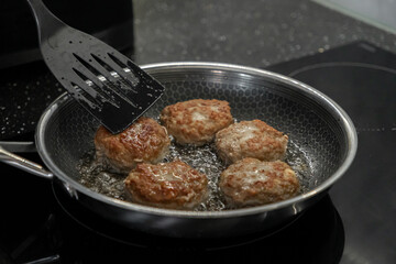 Sizzling golden-brown cutlets cooking in hot oil with a spatula, actively creating a delicious homemade meal in a modern kitchen setting