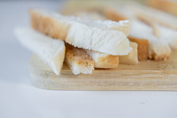 Freshly baked white bread slices with golden crusts are neatly arranged on a natural wooden board, perfect for simple meals or breakfast preparation