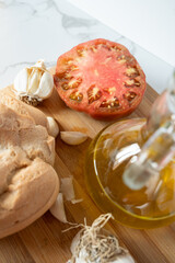 Bread, tomato, garlic and olive oil resting on cutting board showcasing Mediterranean diet