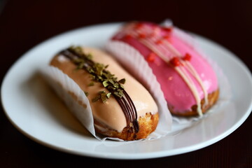 Two sweet donuts on a white plate, topped with colorful icing