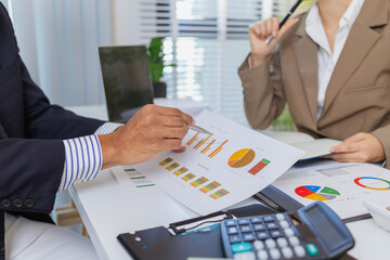 Business colleagues are engaged in a financial meeting, reviewing colorful charts and reports. They...